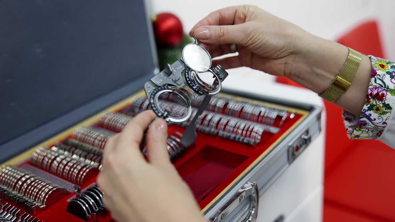 Doctor selecting lenses to the trial frame. Hands of female optometrist picking up test lenses from case for eyesight examination Close-up.
