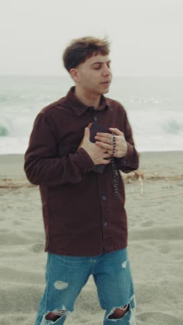 man flipping the pages of the bible book while praying near the ocean