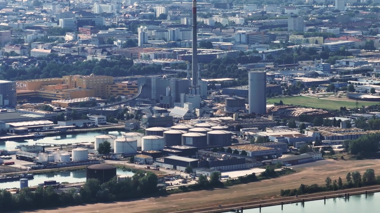 Perspectiva aérea ampla de uma enorme usina siderúrgica e metalúrgica localizada à beira de um rio, exibindo sua extensa infraestrutura
