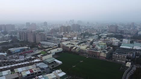 a dense cityscape at dusk with a mix of residential and commercial buildings, overcast sky, aerial view