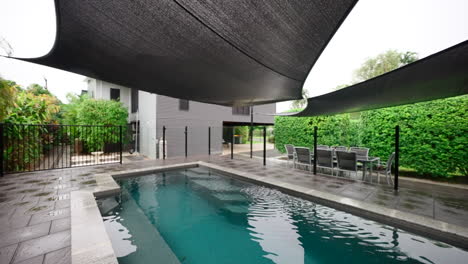 pullback above elegant luxury pool and shade covering draped over outside on rainy day