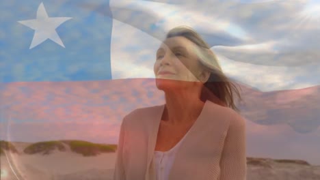 animation of flag of chile over thrilled senior caucasian woman adjusting hair and walking on beach