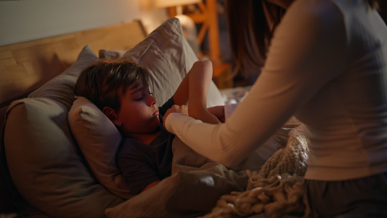 Mother measuring son temperature caring of child health late evening closeup