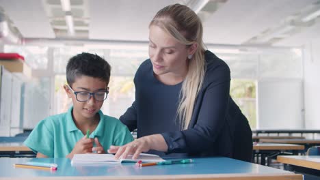 friendly school teacher explaining task to pupil boy