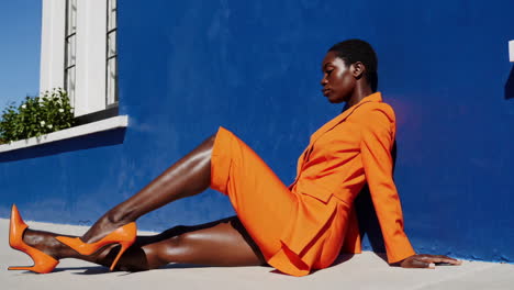 stylish woman in orange suit against a vibrant blue wall