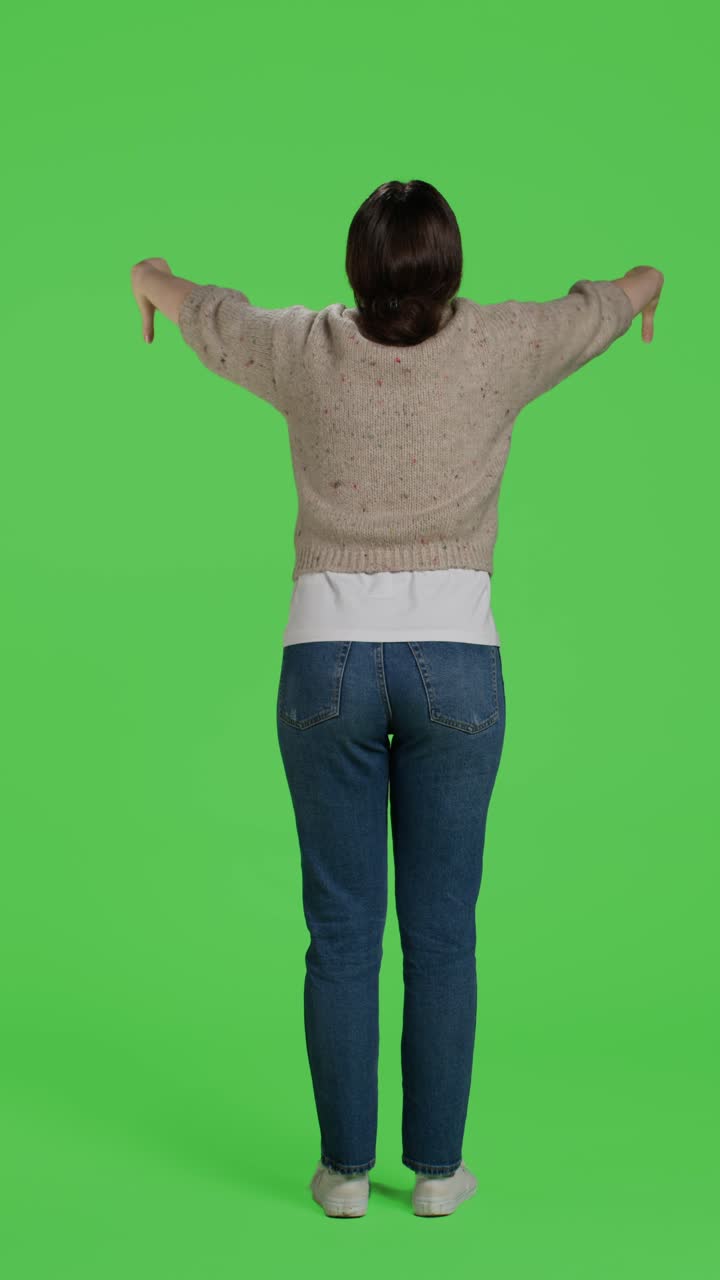 Vertical video: Back view of adult showing thumbs down negative gesture on studio camera