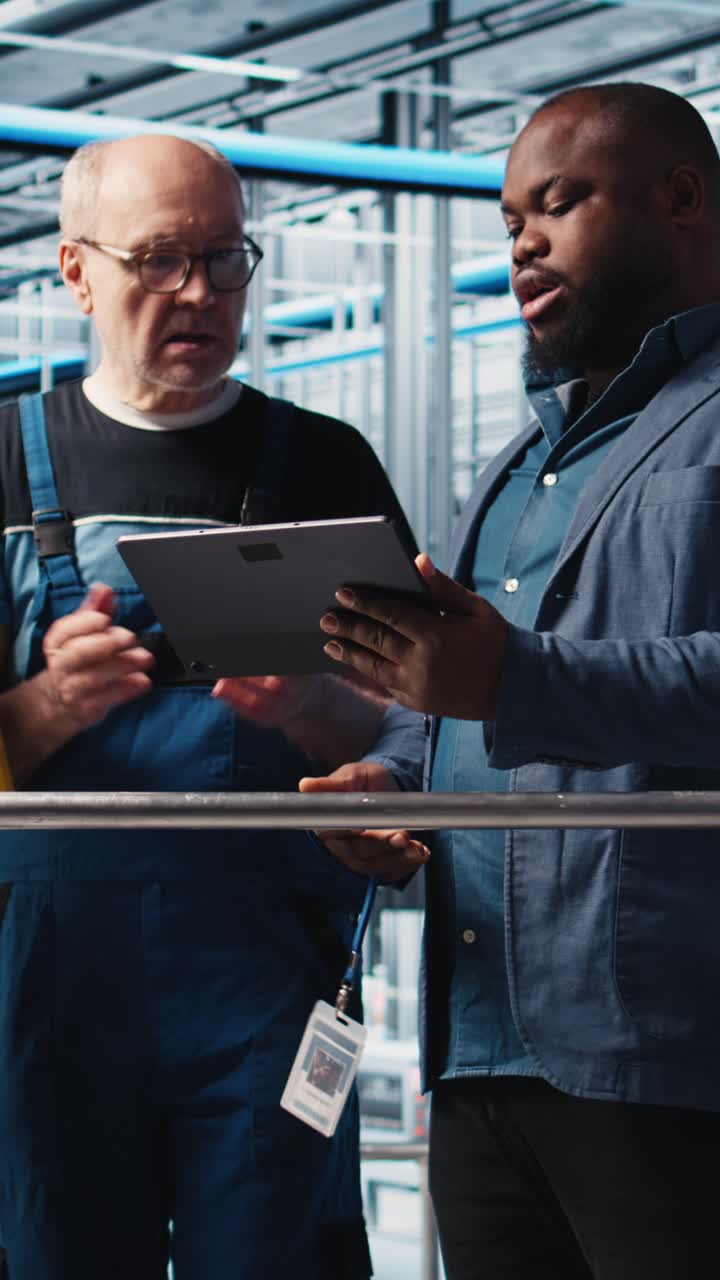 Vertical video Engineers talk with manager overseeing smart factory, showing collected metrics