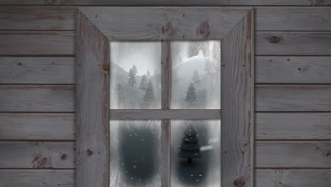 wooden window frame against snow falling over multiple trees on winter landscape