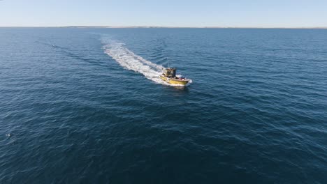 commercial fishing boat sailing on the open sea with backwash on the surface near isla de los pajaros in argentina