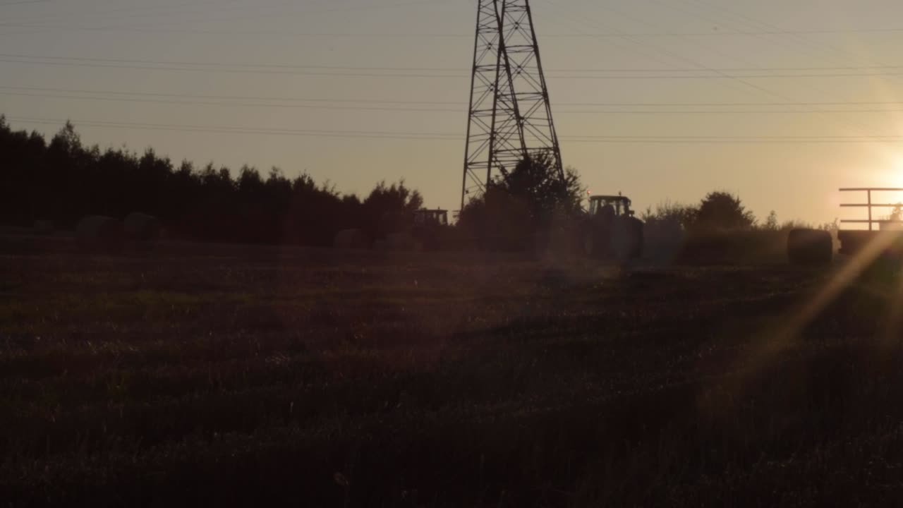 tractores al atardecer en el campo rural al atardecer en el horizonte.