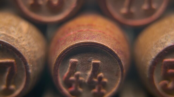 Ripresa macro cinematografica fluida di barilotti di legno del Bingo in fila, pedine di legno, vecchio gioco da tavolo vintage con numeri, numero fortunato 44, slow motion, movimento gimbal commerciale 4K, illuminazione sognante, tilt up.