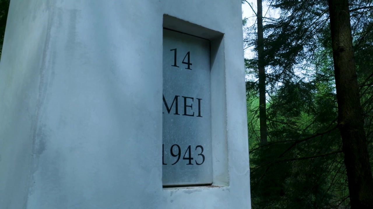 Pilastro commemorativo in pietra con iscrizione della data in un contesto boschivo