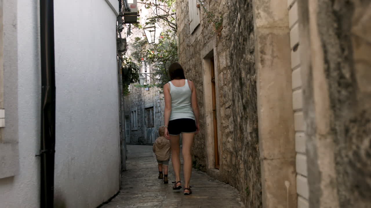 Mother and Child Walking Through a Narrow Alley