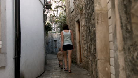 mother and child walking through a narrow alley