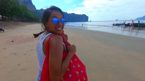 slow motion | beautiful indian girl on a beach in thailand walking towards the water smiling