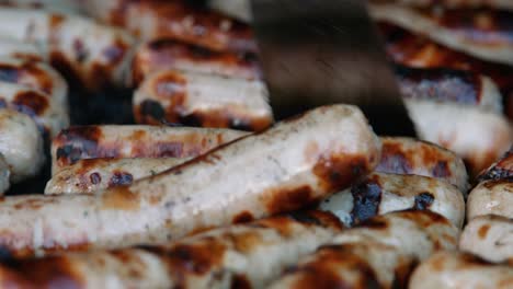 pork sausages being turned on hot bbq by chef