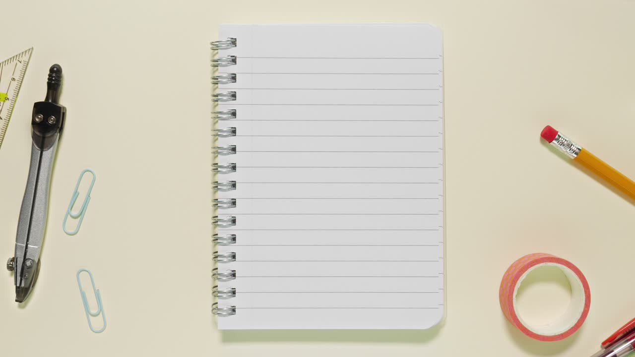 Top-down stop motion of school and office items circling a spiral lined notebook that serves as the copy space