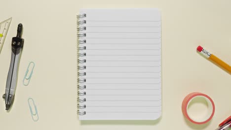 top-down stop motion of school and office items circling a spiral lined notebook that serves as the copy space