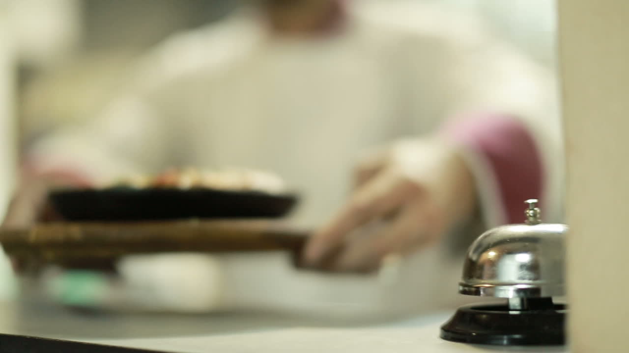 Cook Man Pressing A Bell Indoor. Chef ringing bell at order in the commercial kitchen