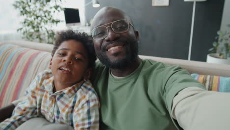 cheerful african american dad and little son chatting on video call