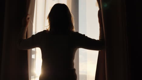 Woman-looks-out-the-window-and-holds-the-curtains-with-her-hands-1