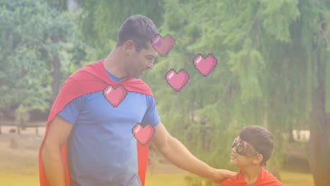 animation of hearts over caucasian father and son in superhero costumes