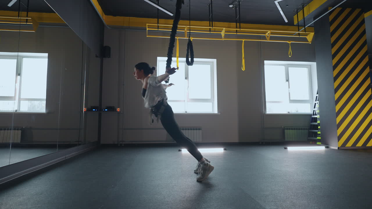 체육관에서 서스펜션 훈련 젊은 스포츠 여성은 피트니스 클럽에서 혼자 훈련하고 체력을 유지하고 있습니다.