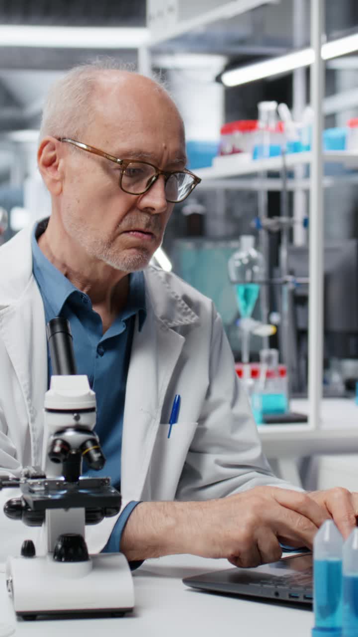 Vertical video Chemical engineer in lab inspecting chemical compounds using laptop