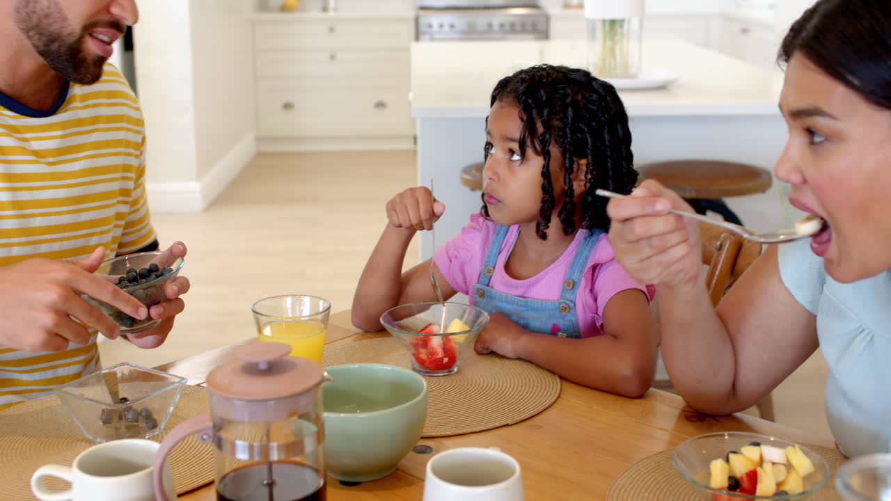 Family enjoying breakfast together at home, sharing fruit and conversation