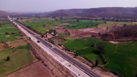 highway road beside agricultural land with mountainous, day time, moving up, push back, drone shot, 4k.