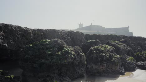 naturaleza mar océano orilla piedras rocas olas arena algas marinas soleado luz del día clif fortaleza viaje tiro inclinado 4k