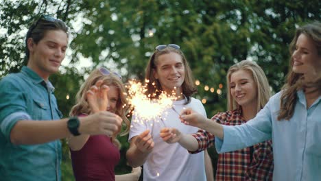 happy friends with sparklers having fun outdoors