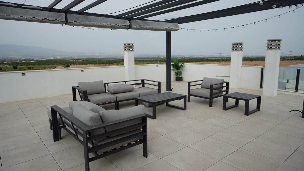 Moderne tagterrasse med udendørs loungemøbler, pergolakonstruktion og åbne panoramiske omgivelser i et minimalistisk boligmiljø.