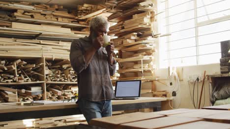 African-american-male-carpenter-drinking-coffee-in-a-carpentry-shop