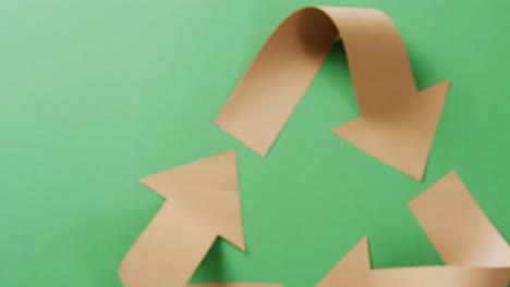 close up of recycling symbol of paper arrows on green background