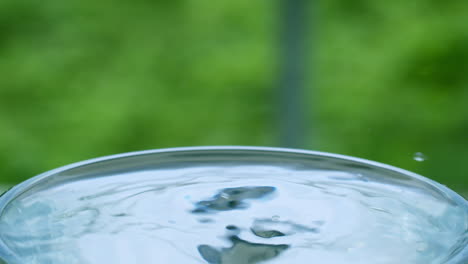 close-up of tiny droplets of water creating ripples and waves in a glass full of water