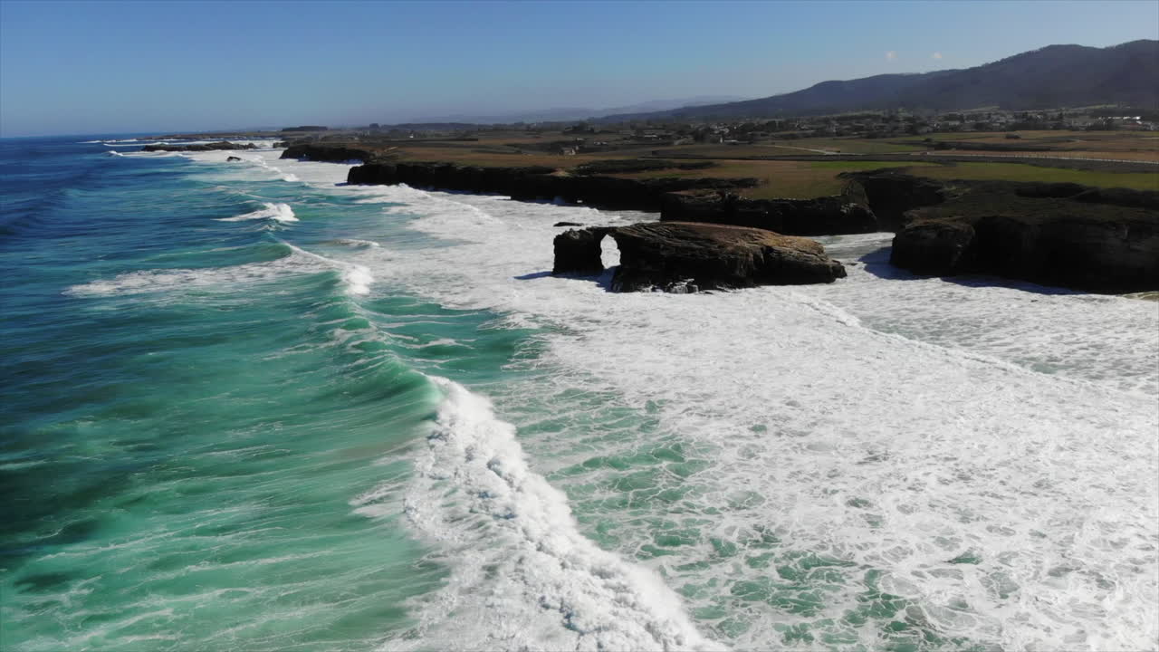 Foamy Ocean Waves Splashing And Crashing At The Rocky Cliffs At Playa de las Catedrales (Beach of the Cathedrals) In Summer At Ribadeo, Galicia, Spain.  - aerial pullback shot
