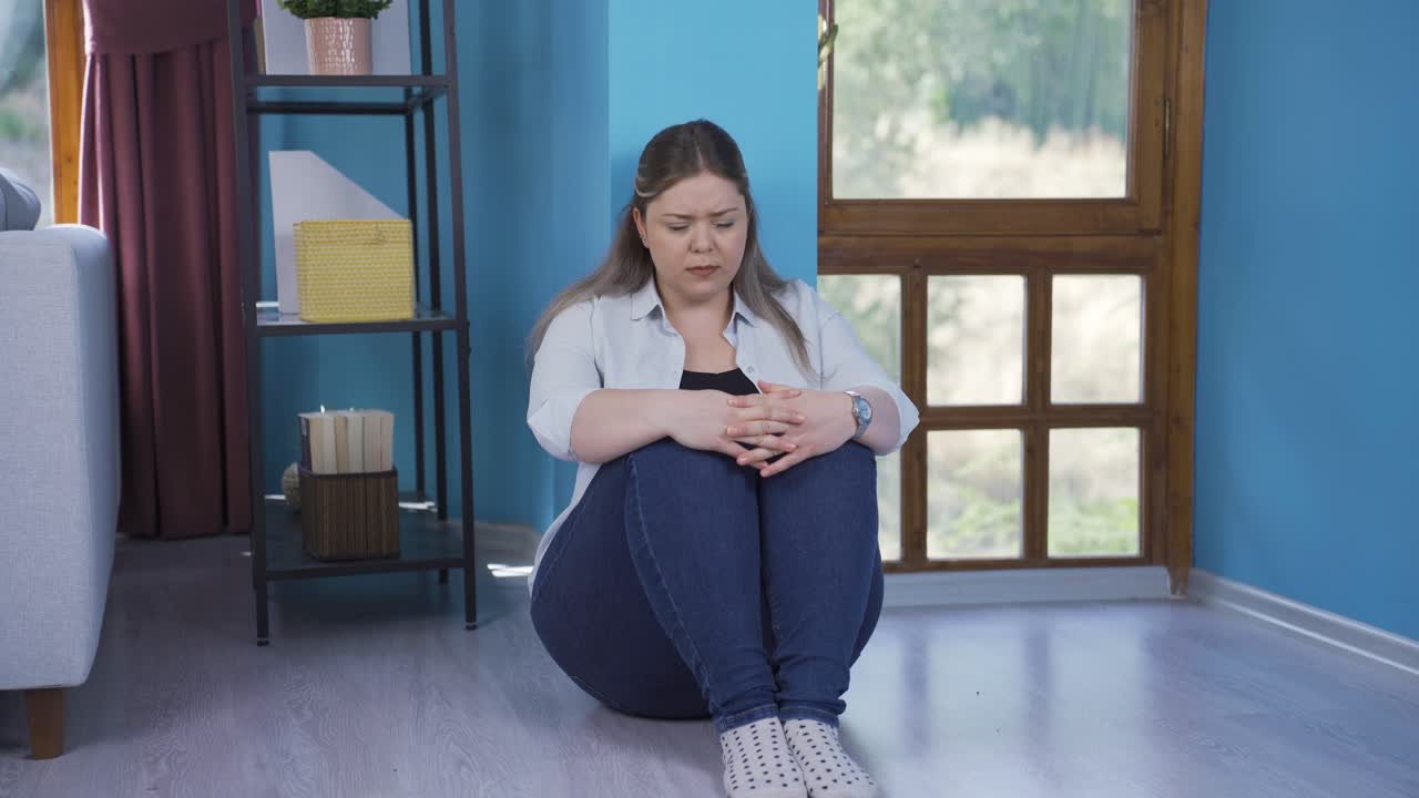 Joven deprimida. Se sienta junto a la pared
