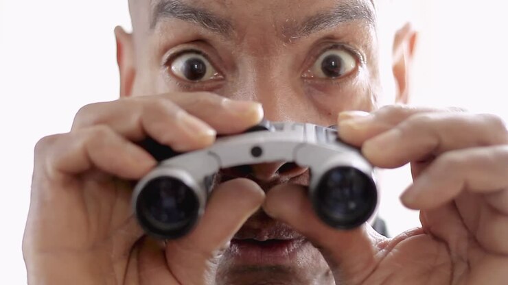 binocolo che guarda attraverso il binocolo con sfondo bianco video d'archivio filmati d'archivio
