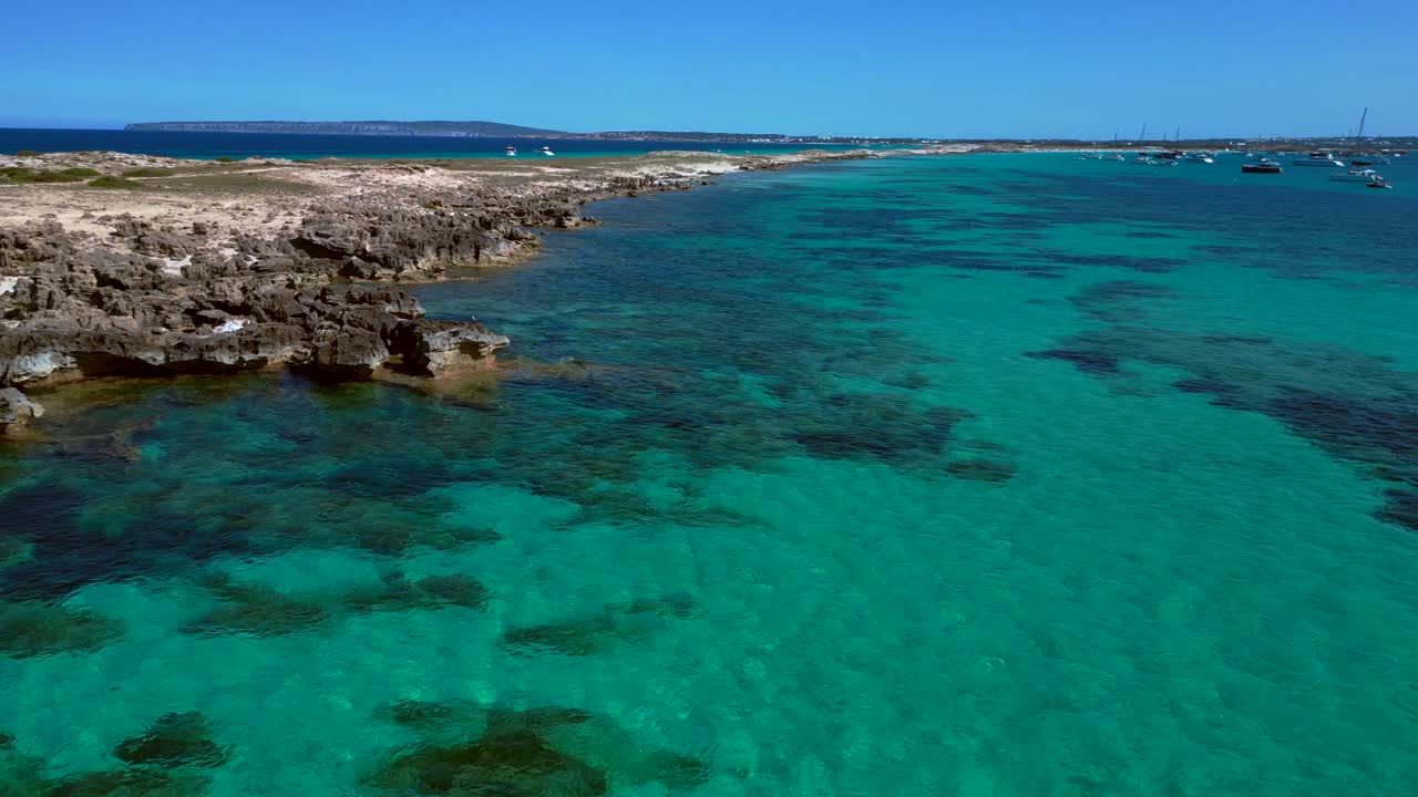 Punta des Borronar beach on Formentera Ibiza island with yachts mooring in clear turquoise water. Great aerial view flight fly reverse overflight flyover drone