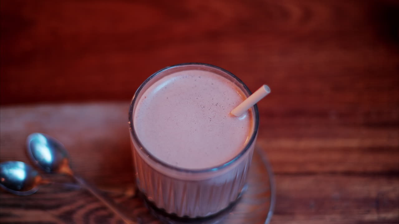 Primo piano di una cioccolata calda in un bicchiere con una cannuccia su un tavolo in un bar. Verticale