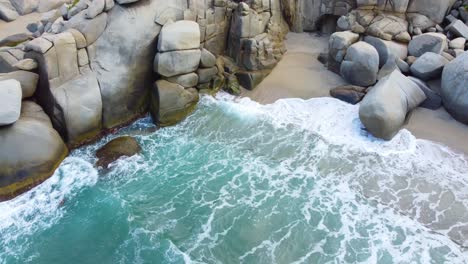 Waves-crashing-against-rocky-shore-in-santa-marta,-colombia,-vibrant-and-serene,-aerial-view