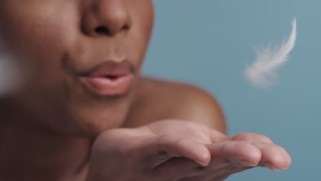 slow motion young african american woman blowing feathers falling on hand skincare concept close up