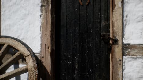 vieja rueda de madera y puerta negra en la casa blanca