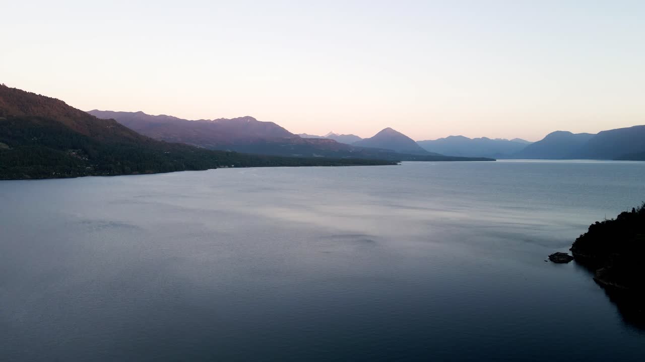 Relaxační panoramatický pohled za modré hodiny na jezero Calafquén v jižním Chile s vlnící se hladinou a horami na obzoru - záběr z dronu.