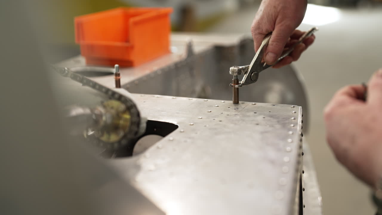 Worker assembling metal components using a wrench, tightening bolts on an industrial machine structure