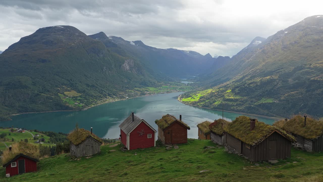 Tradisjonelle trehytter på en grønn fjellside i landlige Norge