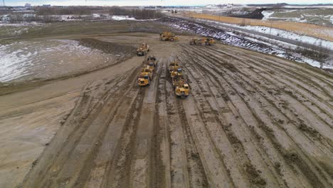 Wheel-tractor-scrappers-work-in-a-construction-site-to-level-out-and-grade-an-area-for-a-new-housing-development-as-seen-from-an-aerial-drone-vantage-point