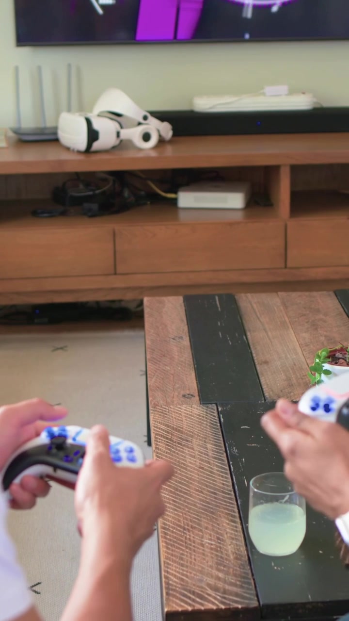 Vertical video: Female entering grabbing controller, two gaming with white controllers at home