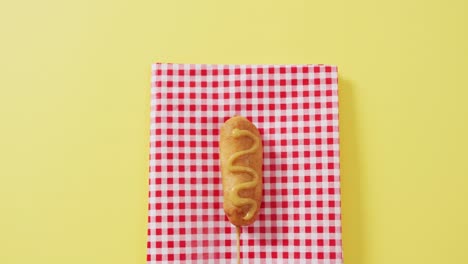 video of corn dog with mustard on a yellow surface